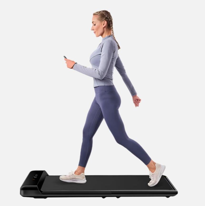 Woman in blue athleisure working out on the C2 WalkingPad with remote in hand. 