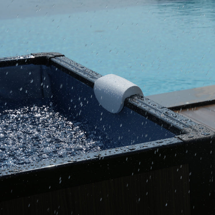 Close up of head rest on side of spa. Water droplets splashing on outside from rain.