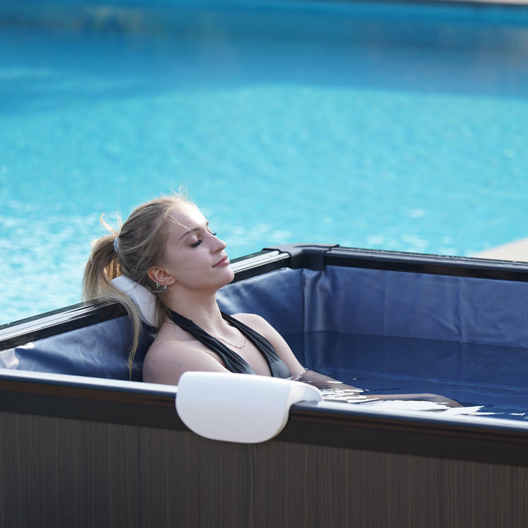 Near side angle of woman relaxing in spa with still water.