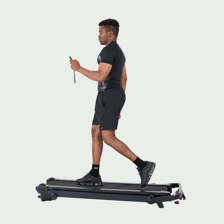 Man walking on treadmill using wireless remote control.