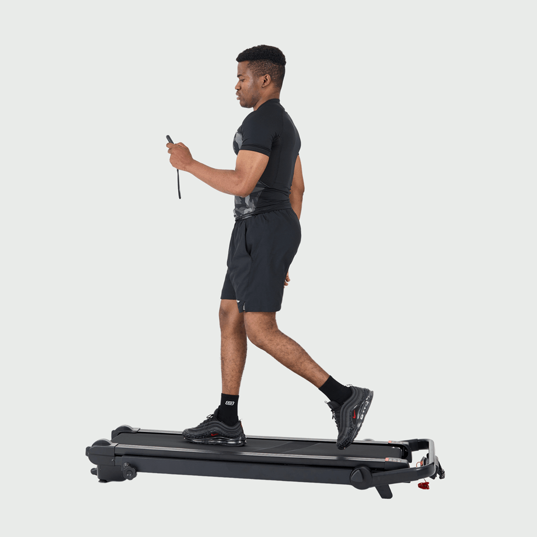 Man walking on treadmill using wireless remote control.